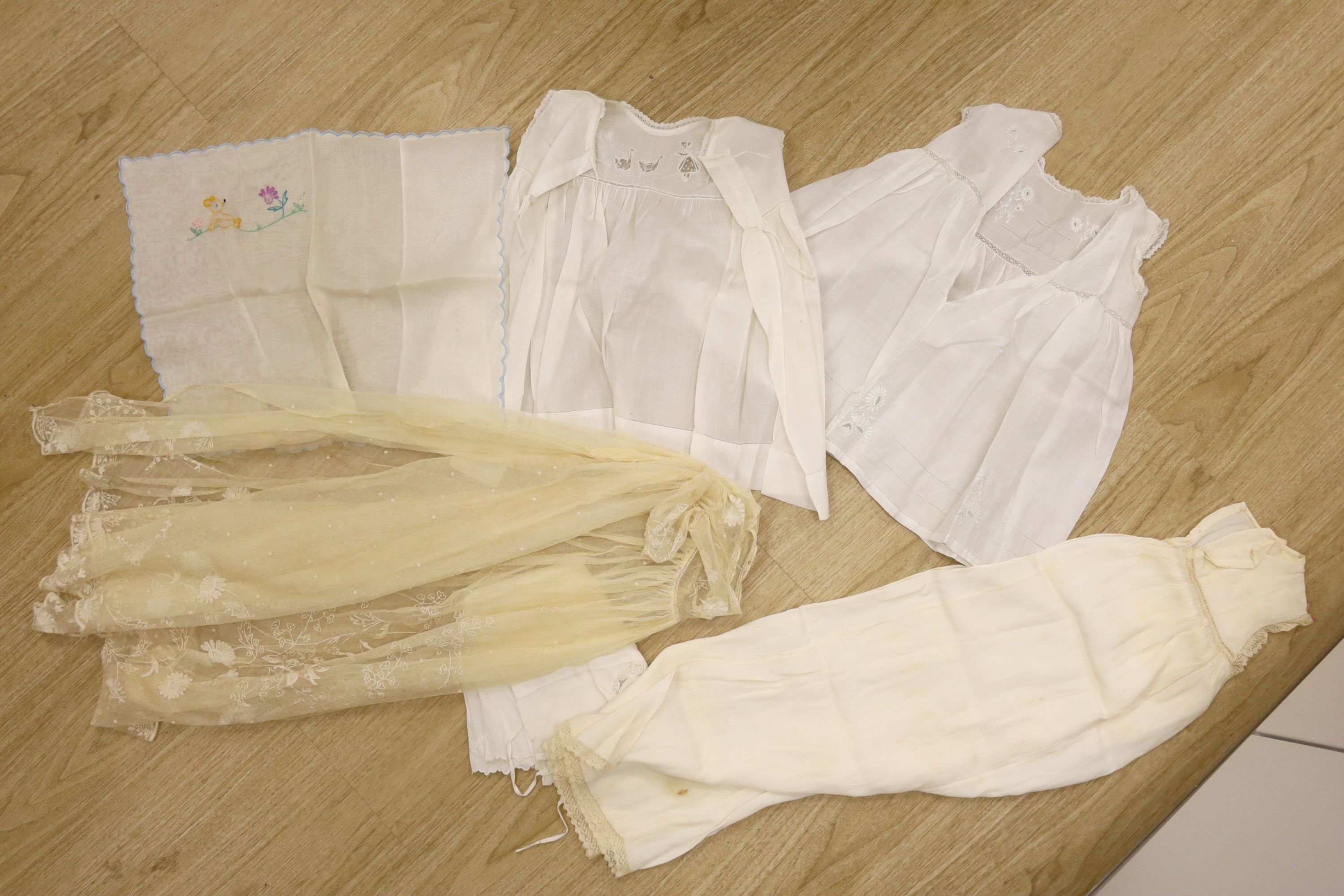 A 1920's needle run embroidered christening gown, on cream net, two whitework baby gowns and a pillow case